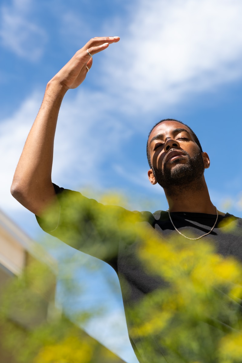 man in yellow and black crew neck shirt raising his right hand trying ways to prevent heat-related workers' compensation claims